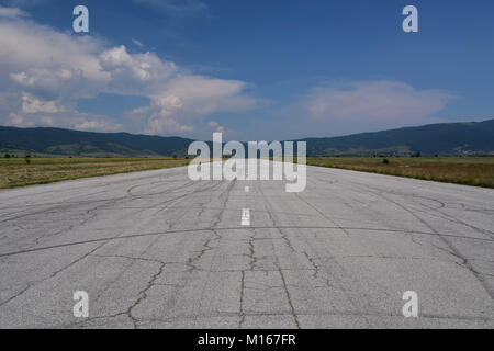 Piste abandonnée utilisé comme piste de rallye. Chaude journée d'été. Les fissures et les traces de pneus de voiture vu sur la surface asphaltée Banque D'Images