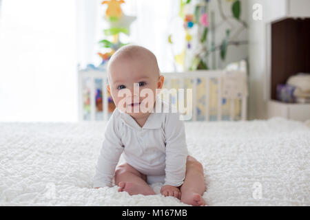 Petit bébé garçon, enfant, jouer à la maison avec de la peluche jouet au lit dans la chambre Banque D'Images