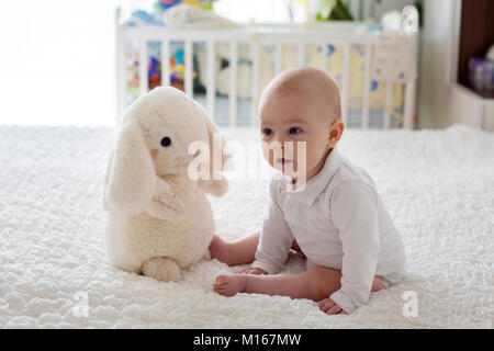 Petit bébé garçon, enfant, jouer à la maison avec de la peluche jouet au lit dans la chambre Banque D'Images