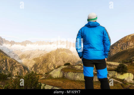 Alpinist se tient pendant l'aube de l'aube en face du majestueux paysage de montagne dans les Alpes Suisses Banque D'Images