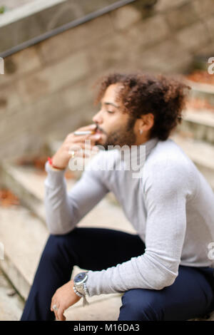 Jeune fumeur toussant sur les mesures avec la cigarette. Banque D'Images