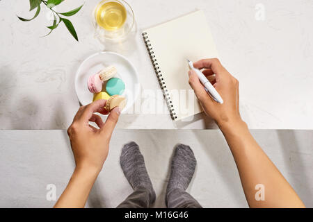 Style minimal de mise à plat de l'ordinateur portable ouvert avec table, croissant et thé. Banque D'Images