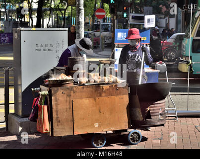 Colporteurs vendre cuisinière châtaignes grillées, des patates douces cuites à la vapeur et d'œufs, à l'angle d'une rue à Kowloon, Hong Kong Banque D'Images