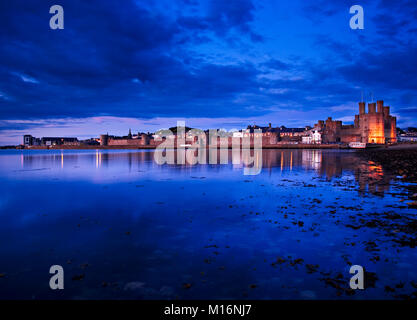 Château de Caernarfon au crépuscule sur la côte nord du Pays de Galles, avec des reflets dans la mer Banque D'Images