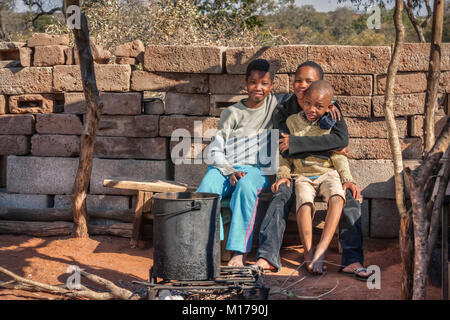 Assis à l'intérieur de la famille africaine la cuisine en plein air dans le village, au Botswana Banque D'Images