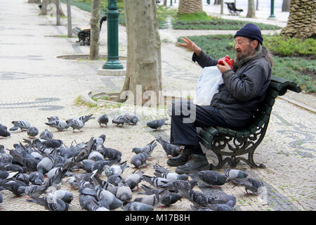 Lisbonne, Portugal.Vers avril 2014.Homme sans abri partageant son repas avec des oiseaux.Photo prise sur la route Rua da Liberdade à Lisbonne Portugal Banque D'Images