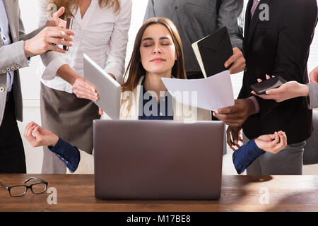 Young Businesswoman entouré par des mains qui lui donne beaucoup de travail dans Office Banque D'Images