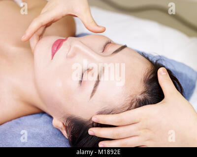 Close-up of beautiful young asian woman receiving massage du visage au spa de beauté, les yeux fermés. Banque D'Images