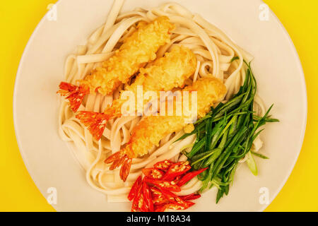 Crevettes Tempura de style japonais avec les nouilles Udon Piment et oignons de printemps sur fond jaune Banque D'Images