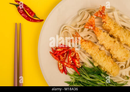 Crevettes Tempura de style japonais avec les nouilles Udon Piment et oignons de printemps sur fond jaune Banque D'Images