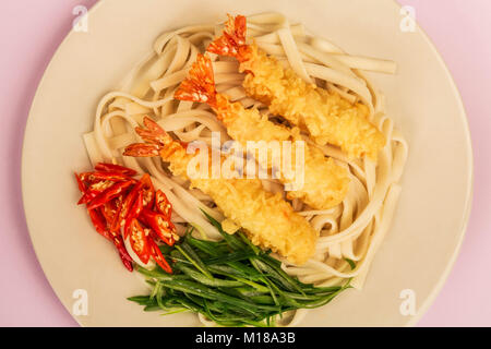 Crevettes Tempura de style japonais avec les nouilles Udon Piment et oignons de printemps sur un fond lilas Banque D'Images