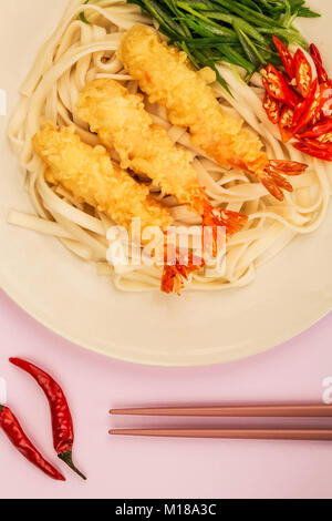 Crevettes Tempura de style japonais avec les nouilles Udon Piment et oignons de printemps sur un fond lilas Banque D'Images