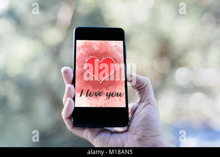 Valentines Day vente fond avec woman holding smartphone avec coeur illustration avec les mots je t'aime à l'écran immersive contre nature ba Banque D'Images