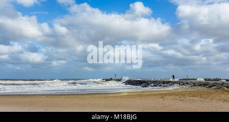 La côte du New Jersey à Manasquan Inlet. L'océan est rugueux comme il y a une tempête sur la mer. Il y a une seule personne debout sur une pierre jetée. Banque D'Images