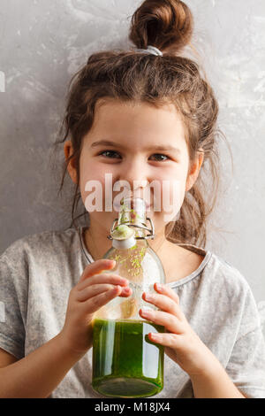 Belle petite fille heureuse saine boissons smoothie aux fruits légumes verts. Santé des enfants végétaliens concept. Banque D'Images