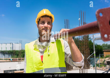 Ouvrier transportant une lourde barre métallique lors des travaux sur la Banque D'Images