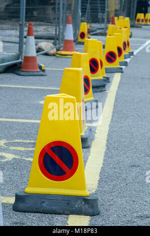 Un niveau bas sur une rangée de petits cônes de travaux routiers jaune avec un "pas d'attente' signe sur chaque Banque D'Images