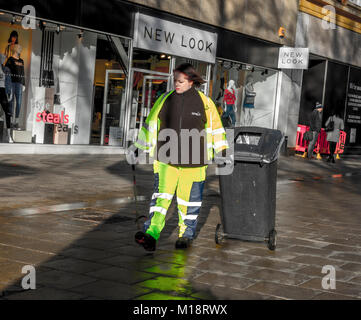 Jeune femme / homme refuser et collecte des déchets / street cleaner, le port de vêtements fluorescents. Le centre-ville de Peterborough, Cambridgeshire, Angleterre, Royaume-Uni. Banque D'Images