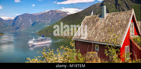 Chalet rouge contre le navire de croisière en fjord, Flam, Norvège Banque D'Images