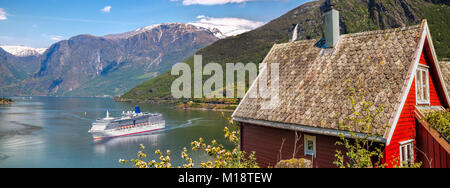 Chalet rouge contre le navire de croisière en fjord, Flam, Norvège Banque D'Images