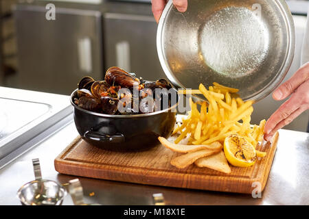 Verser les frites sur planche de bois. Banque D'Images