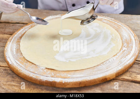 Verser la sauce sauce de voile de croûte à pizza. Banque D'Images