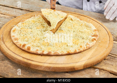 Close up spicy pizza slice en tenant par la spatule. Banque D'Images