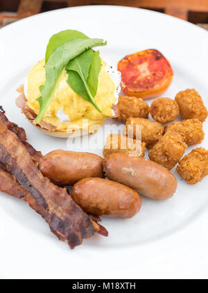 Délicieux petit déjeuner avec des œufs Bénédicte, bacon, saucisse, et paillasson de pommes de terre Banque D'Images