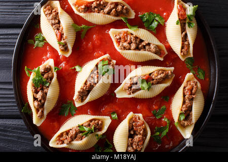 Shell pâtes conchiglioni avec remplissage de la viande hachée dans la sauce marinara close-up dans le plat. Haut horizontale Vue de dessus Banque D'Images