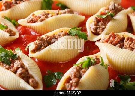 Shell pâtes conchiglioni avec remplissage de la viande hachée dans la sauce marinara close-up horizontale dans le plat. Banque D'Images