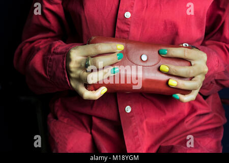 Woman wearing red shirt tenant une affaire esthétique, studio shot recadrée Banque D'Images