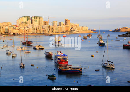 Bateaux amarrés dans la Crique de Sliema, La Valette, Malte avec les hôtels éclairées par le soleil couchant Banque D'Images