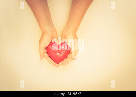 Les mains de quelqu'un holding red burning heart, vue d'en haut, aux couleurs rétro Banque D'Images