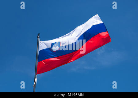 Drapeau de la Slovénie le mât de forme dans le vent. Drapeau officiel national slovène sur fond de ciel bleu. Symbole patriotique, bannière Banque D'Images