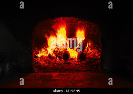 La combustion de bois dans un four en brique, feu flamme libre. Flamme de brûler du bois dans une cheminée en pierre à partir de briques réfractaires Banque D'Images