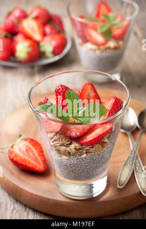 Petit déjeuner santé diète. chia pudding, des fraises et du muesli dans un verre , des fraises fraîches sur fond de bois vieux Banque D'Images