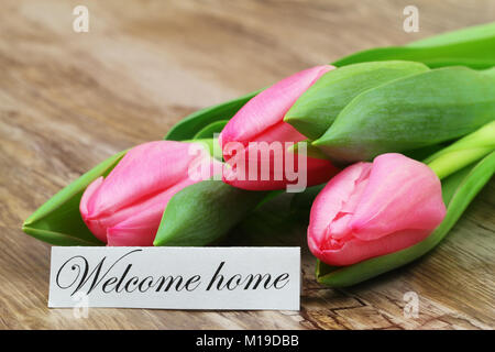 Bienvenue accueil carte avec trois tulipes roses sur la surface en bois Banque D'Images