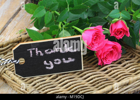 Merci écrit sur mini tableau noir avec une rose rose sur le plateau en osier Banque D'Images