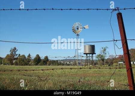 Moulin à vent et tankstand au paddock, Queensland, Australie. Les moulins à vent sont couramment utilisées pour pomper de l'eau à partir de barrages ou les alésages d'auges pour le bétail. Banque D'Images