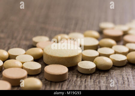 Heap of assorted capsules beige sur table en bois. Les pilules sont faire une ligne ou un chemin. Concept de façon, bien sûr. Banque D'Images