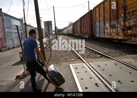 Les piétons attendre qu'un train de marchandises de l'Union Pacific transportant des marchandises en provenance du Mexique passe de Nogales, Sonora, Mexique, à Nogales, Arizona, USA, au Banque D'Images