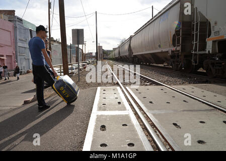 Les piétons attendre qu'un train de marchandises de l'Union Pacific transportant des marchandises en provenance du Mexique passe de Nogales, Sonora, Mexique, à Nogales, Arizona, USA, au Banque D'Images