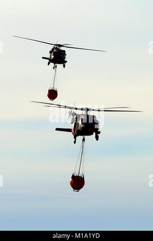 Une paire de Californie National Guard hélicoptères UH-60 Black Hawk de la Compagnie B, 1er Bataillon, 140e Régiment d'aviation, retour à l'aéroport de Camarillo de Camarillo, Californie, dimanche, 10 décembre 2017, après avoir fait des gouttes d'eau sur le feu Thomas dans le comté de Ventura. (U.S. Photo de la Garde nationale aérienne Aviateur Senior Housman Crystal) Banque D'Images