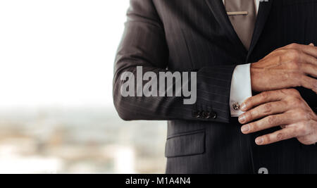 Close up of man in suit ajuster sa chemise bouton. Cropped shot of woman in suit son réglage de la manchette. Banque D'Images