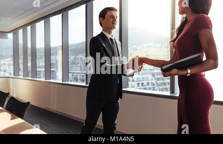 Young businessman shaking hands with female colleague après réunion en salle du Conseil. Après poignée de réunion réussie. Banque D'Images