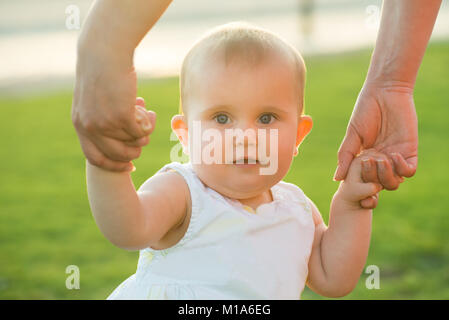 Portrait Of A Cute Baby Girl's main courante par sa mère à l'extérieur Banque D'Images