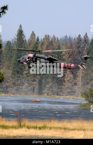 La Californie de l'armée et de la Garde nationale la lutte contre les incendies d'aéronefs et leurs équipages à partir de la 129e Escadre de sauvetage, hors de Moffett Field, et le 3-140ème bataillon de l'Aviation, hors de Los Alamitos, faire d'une base d'étape de forêt près de Redding, en Californie, le 24 août 2012, où ils maintiennent leurs oiseaux, reste, et de prendre le ciel avec des seaux d'eau gigantesque rempli de dip et sites locaux ont chuté sur la ligne de feu. Le citoyen soldats et aviateurs canadiens aident CALFIRE et autres organismes locaux à la lutte contre de nombreux incendies dans le Golden State, région montagneuse du nord. (Photo de la Garde nationale aérienne/Master Sg Banque D'Images