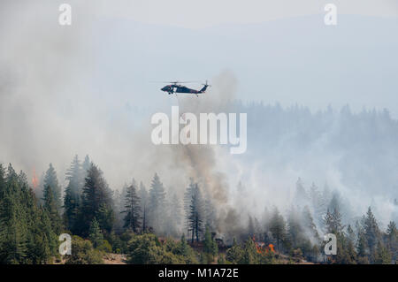 La Californie de l'armée et de la Garde nationale la lutte contre les incendies d'aéronefs et leurs équipages à partir de la 129e Escadre de sauvetage, hors de Moffett Field, et le 3-140ème bataillon de l'Aviation, hors de Los Alamitos, faire d'une base d'étape de forêt près de Redding, en Californie, le 24 août 2012, où ils maintiennent leurs oiseaux, reste, et de prendre le ciel avec des seaux d'eau gigantesque rempli de dip et sites locaux ont chuté sur la ligne de feu. Le citoyen soldats et aviateurs canadiens aident CALFIRE et autres organismes locaux à la lutte contre de nombreux incendies dans le Golden State, région montagneuse du nord. (Photo de la Garde nationale aérienne/Master Sg Banque D'Images