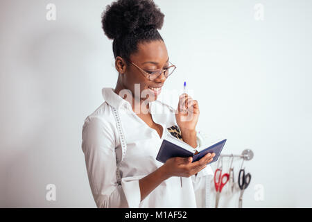 Jeune fille africaine couturière prendre des notes à l'ordinateur portable. designer croquis dessin Banque D'Images