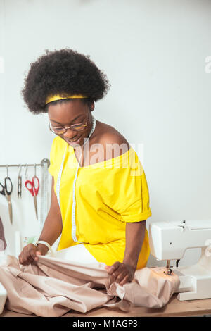 Femme africaine à la couturière et de tissus roses au comité permanent en atelier Banque D'Images
